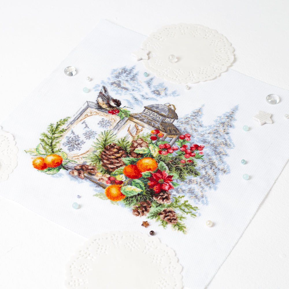 Bordado en punto de cruz de farolillo con plantas de navidad, piñas y un pequeño pájaro de campo de Magic Needle