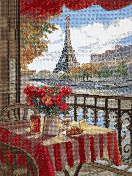 Kit de punto de cruz Aine París Soleado con escena de terraza parisina, mesa con desayuno, flores y Torre Eiffel de fondo.