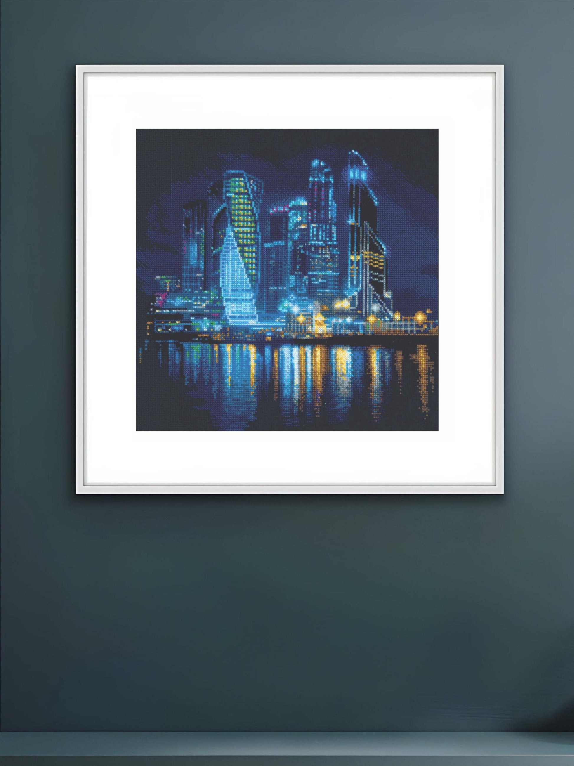 Kit de punto de cruz RIOLIS Ciudad Nocturna con rascacielos iluminados y reflejos sobre el mar en una vista nocturna panorámica.