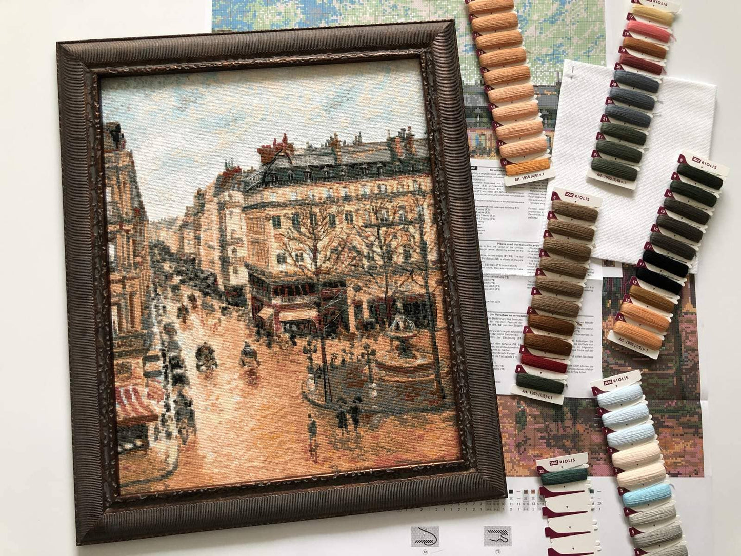 Kit de punto de cruz RIOLIS “Calle Saint-Honoré Pissarro” con calle y plaza francesa, fuente central y carruajes tirados por caballos, estilo principios del siglo XX.