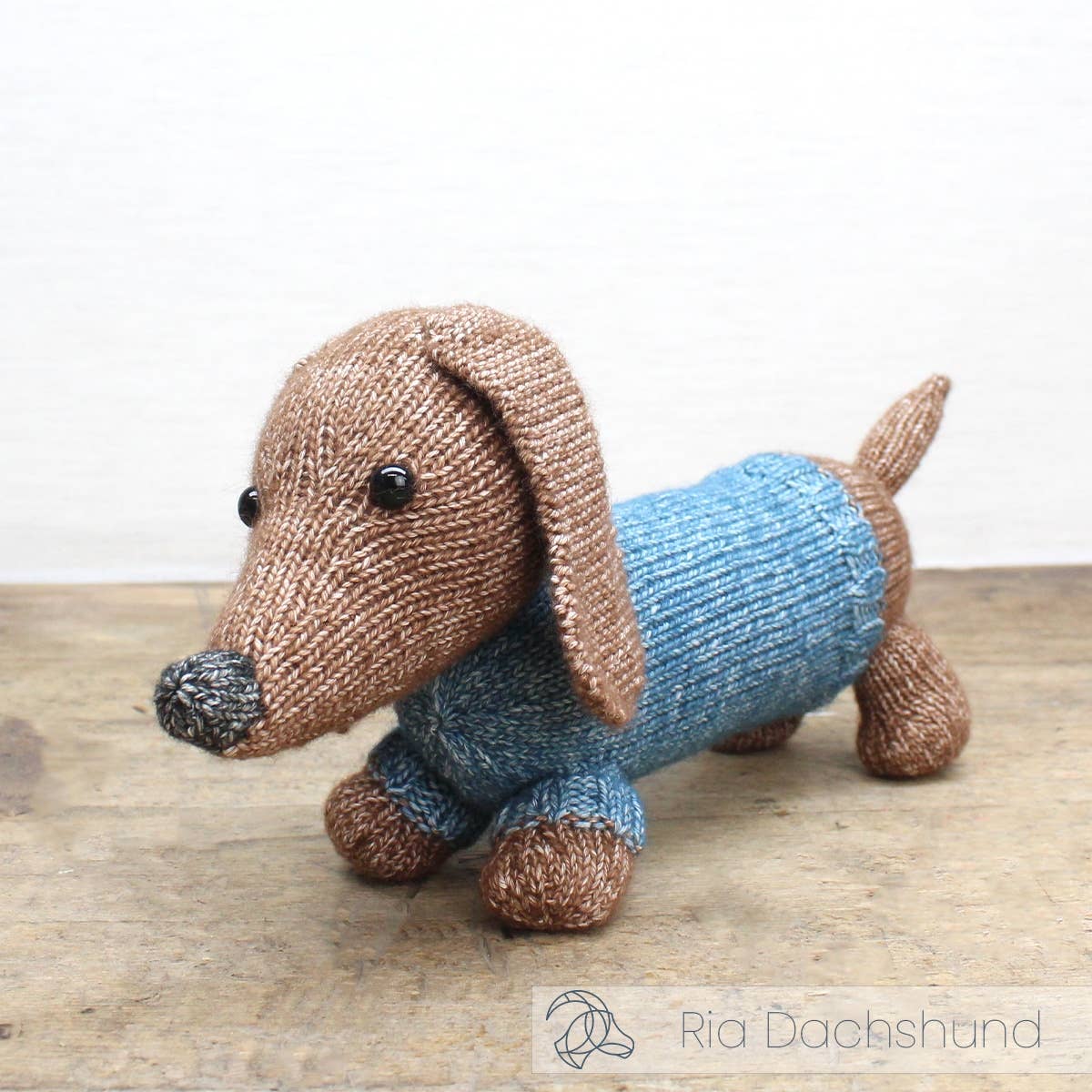Kit de tricot Hardicraft Ria Dachshund con perro salchicha tejido en tonos marrón y azul, ideal como regalo artesanal o decoración.