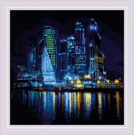 Kit de punto de cruz RIOLIS Ciudad Nocturna con rascacielos iluminados y reflejos sobre el mar en una vista nocturna panorámica.