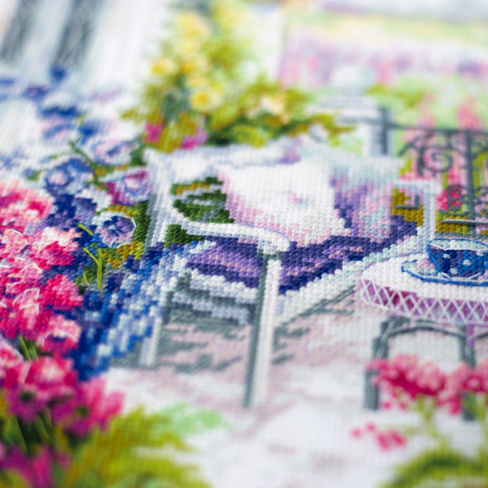 Bordado en punto de cruz de una acogedora terraza con flores en tonos lilas y rosas de Magic Needle