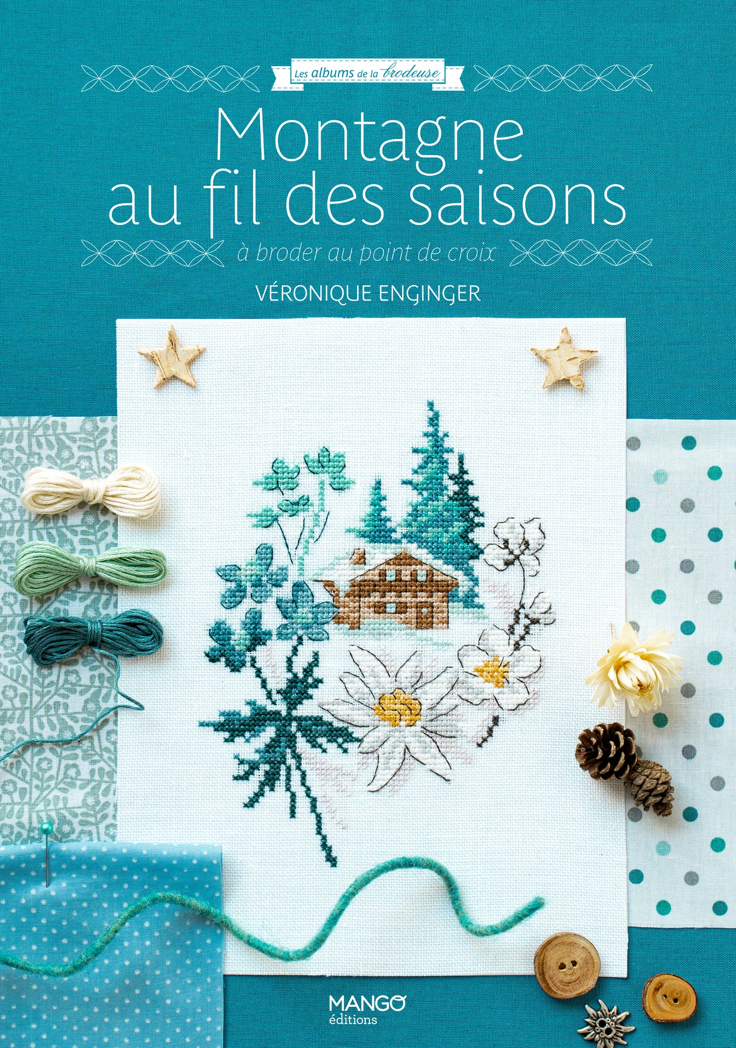 Portada del libro “Montagne au fil des saisons” de Véronique Enginger (Mango Éditions): 20 patrones alpinos en punto de cruz con chalets, flores y pinos, estilo retro.
