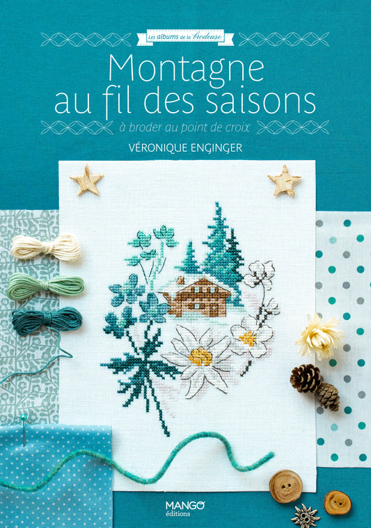 Portada del libro “Montagne au fil des saisons” de Véronique Enginger (Mango Éditions): 20 patrones alpinos en punto de cruz con chalets, flores y pinos, estilo retro.