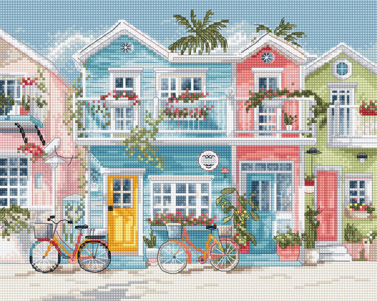 Kit de punto de cruz Letistitch Beach Bliss con fachadas de casas costeras en azul, rosa y verde, balcones floridos y bicicletas de verano en tonos pastel.