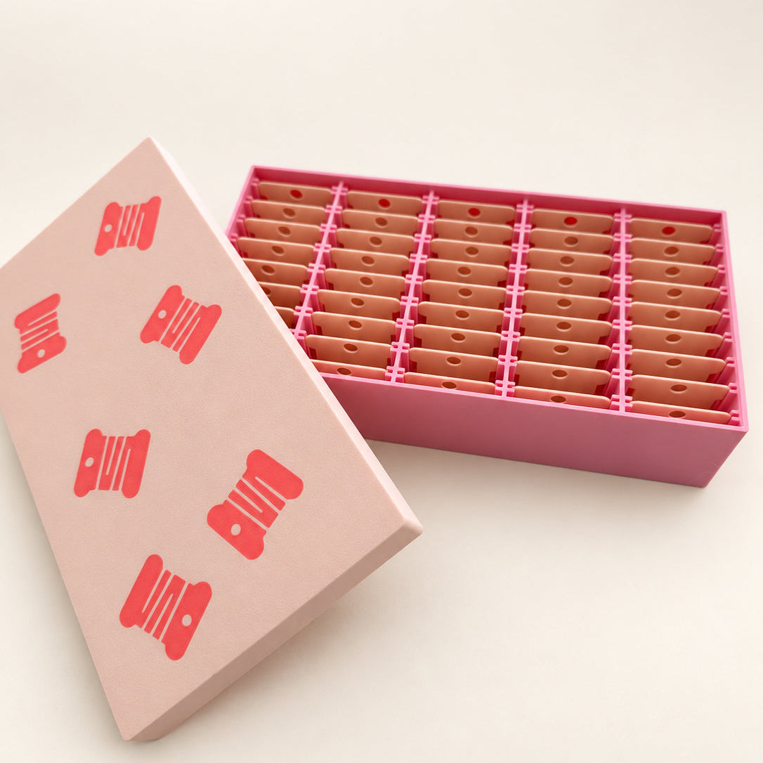 Caja organizadora rosa y beige abierta con 45 espacios para bobinas de hilo