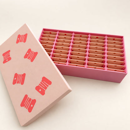 Caja organizadora rosa y beige abierta con 45 espacios para bobinas de hilo