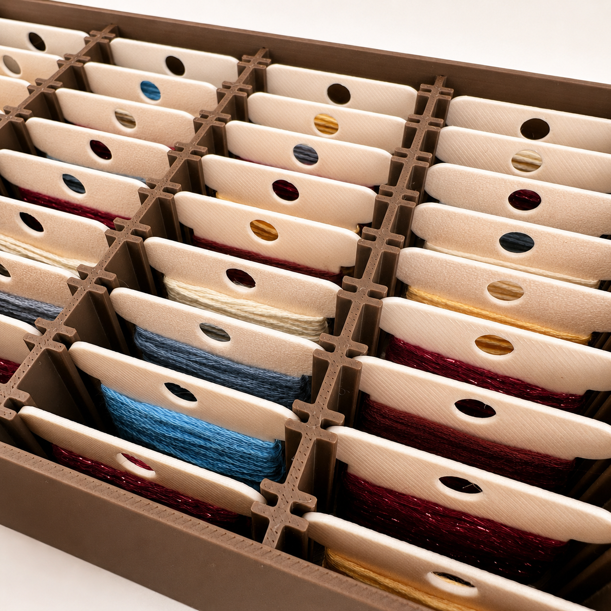 Detalle interior de la caja organizadora con bobinas de hilos de bordado