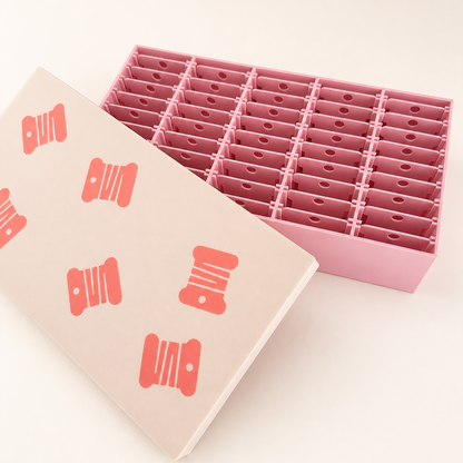 Caja organizadora rosa y beige abierta con 45 espacios para bobinas de hilo