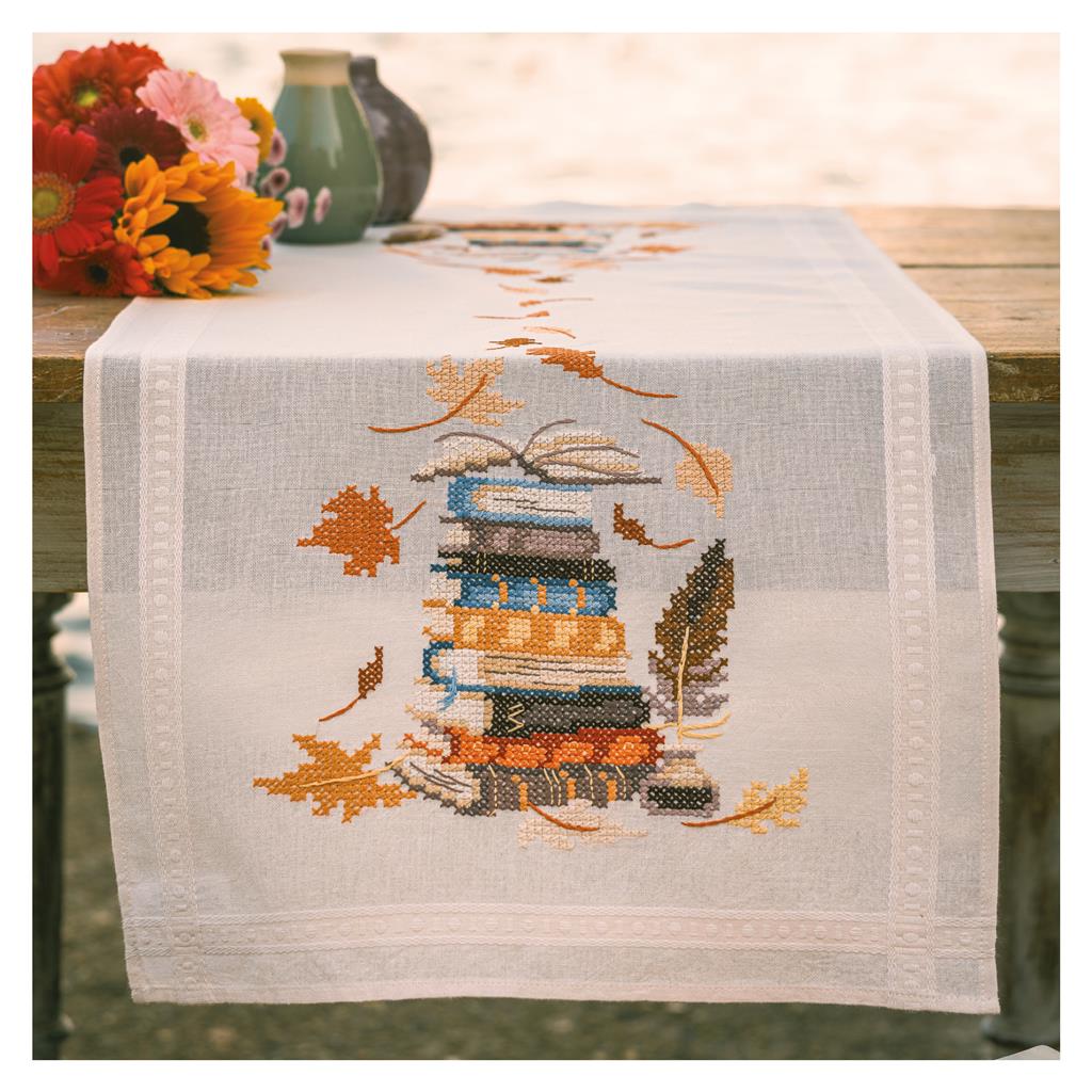 Camino de mesa en punto de cruz Vervaco Libros y Hojas de Otoño con diseño de libros apilados y hojas otoñales bordadas.