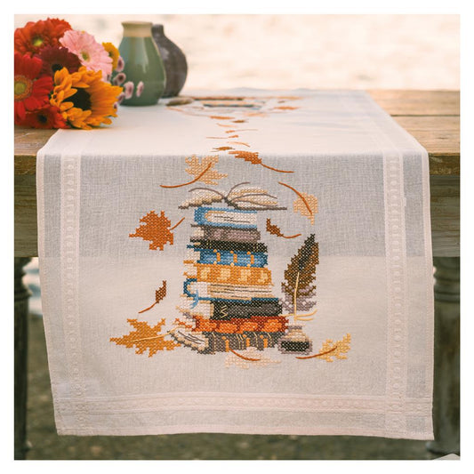 Camino de mesa en punto de cruz Vervaco Libros y Hojas de Otoño con diseño de libros apilados y hojas otoñales bordadas.