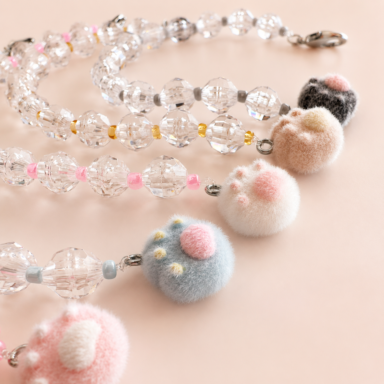 Buscatijeras para bordado con abalorios transparentes, cierre metálico y charms de huella de gato en cinco colores pastel.