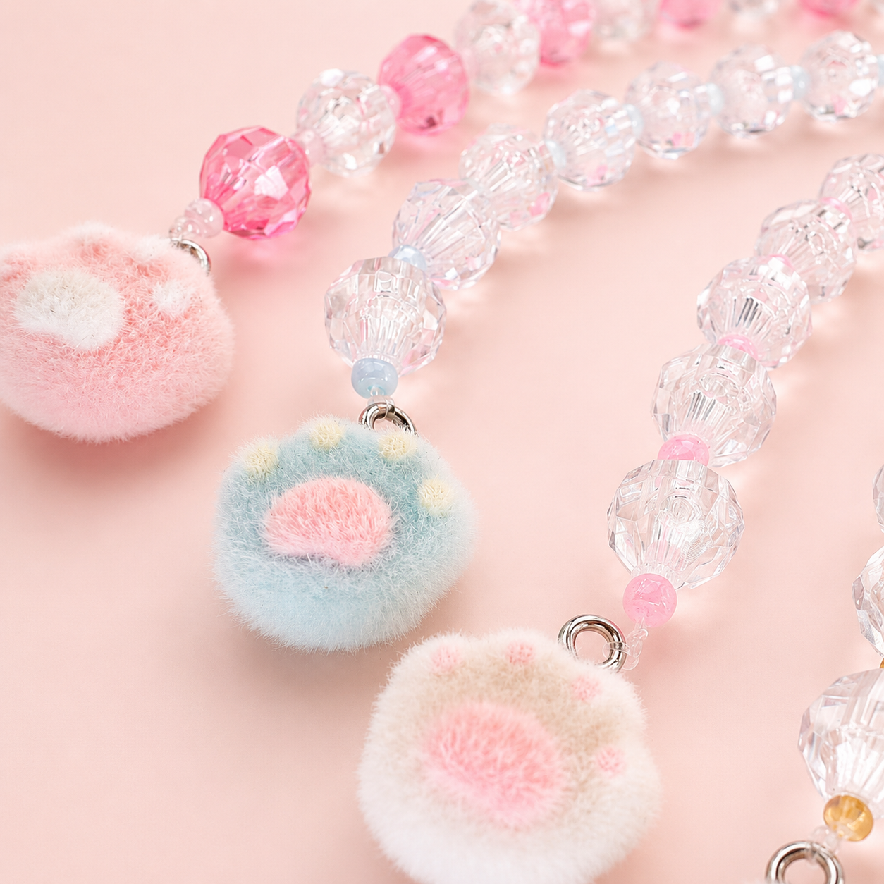 Imagen macro de buscatijeras con abalorios de cristal transparentes y charms de huella de gato para labores creativas.