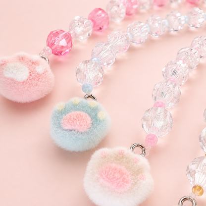 Imagen macro de buscatijeras con abalorios de cristal transparentes y charms de huella de gato para labores creativas.