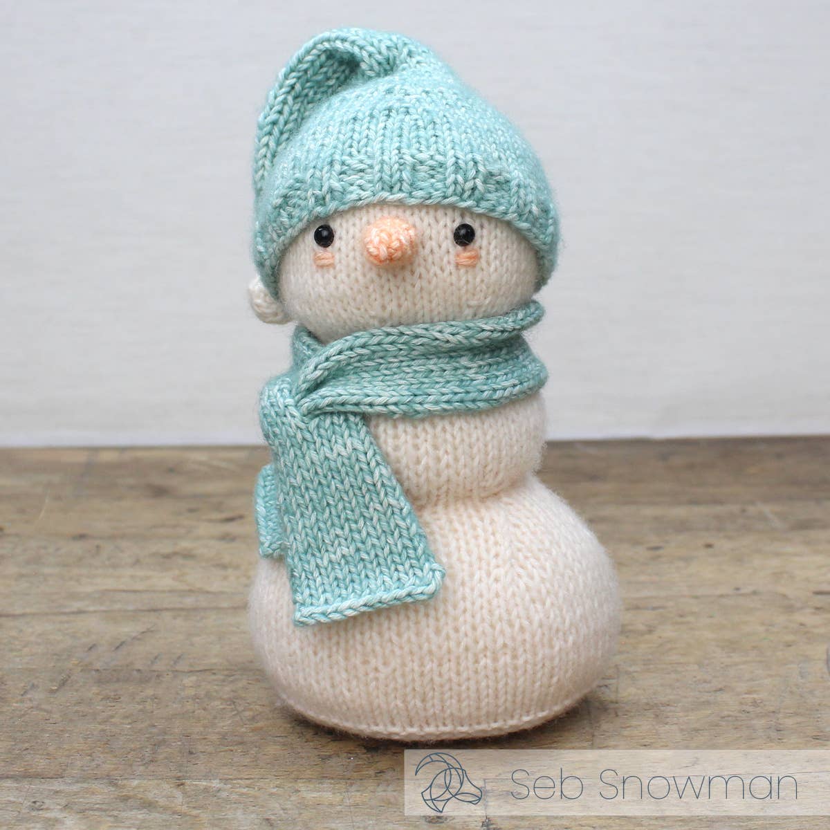 Kit de tricot Hardicraft Seb Snowman con muñeco de nieve tejido en tonos blancos y azules, ideal para decoración navideña.