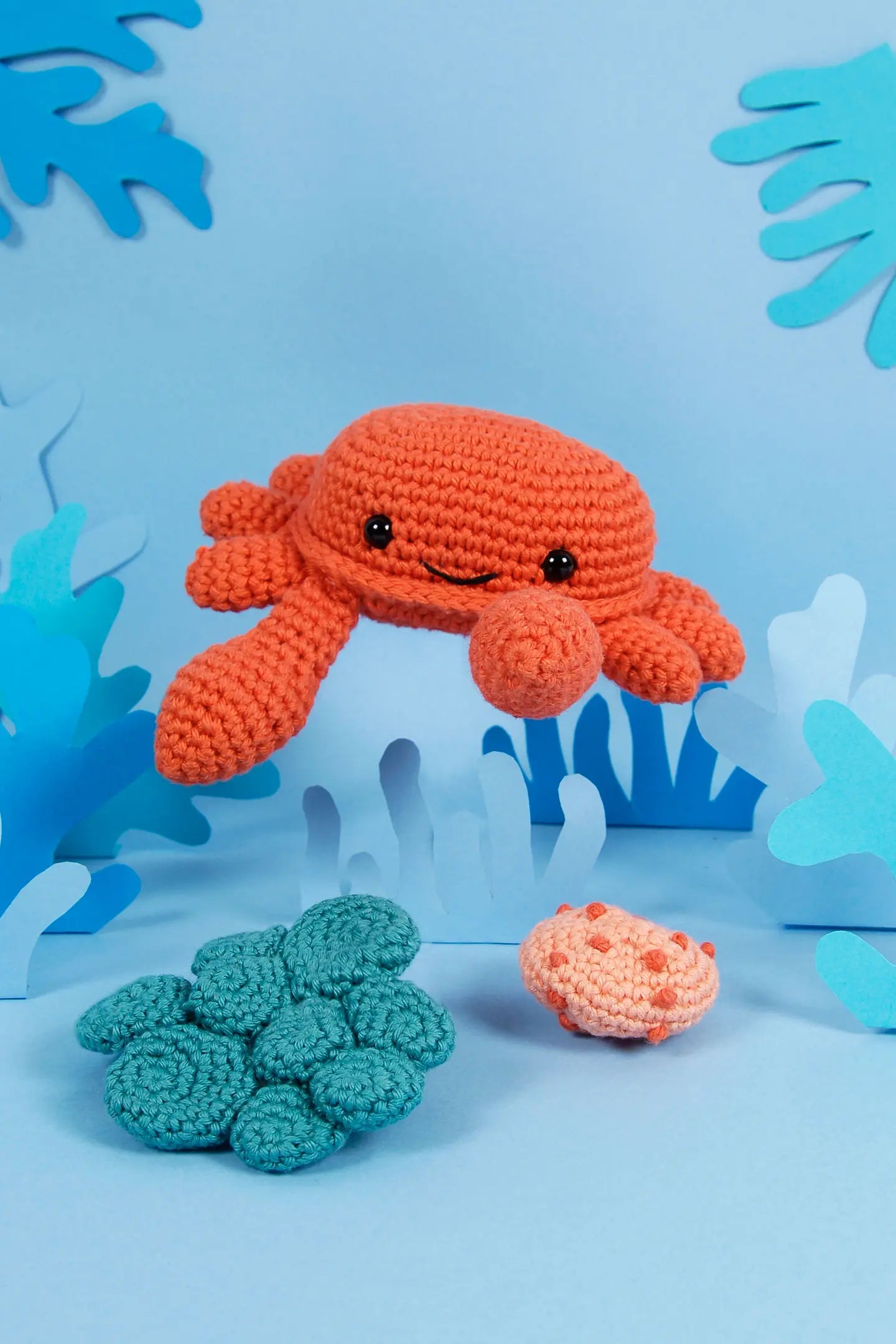 Kit de amigurumi DMC Cangrejo con un cangrejo naranja y corales tejidos a ganchillo en tonos turquesa y coral