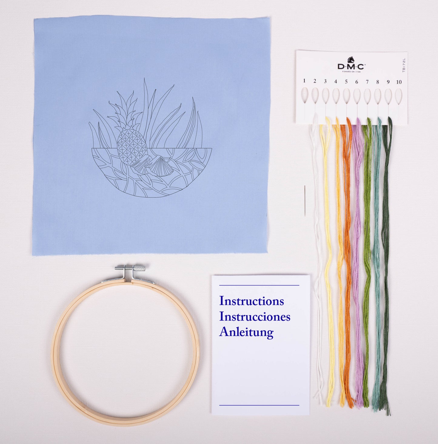 Contenido del kit de bordado DMC Piña con tela estampada azul, hilos Mouliné Spécial, bastidor, aguja e instrucciones