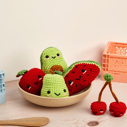 Kit de amigurumi de DMC para tejer cinco frutas con caritas sonrientes, incluye hilos de algodón, ganchillo de 3 mm y ojitos de seguridad, perfecto para crear regalos educativos o decoraciones coloridas.