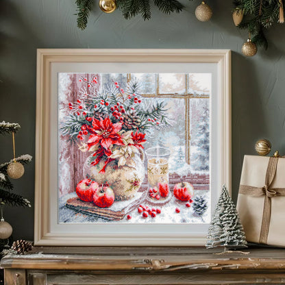 Kit de Punto de Cruz Magic Needle “A Candle Was Burning” 70-50 con diseño navideño de vela, flores y manzanas sobre una mesa junto a una ventana.