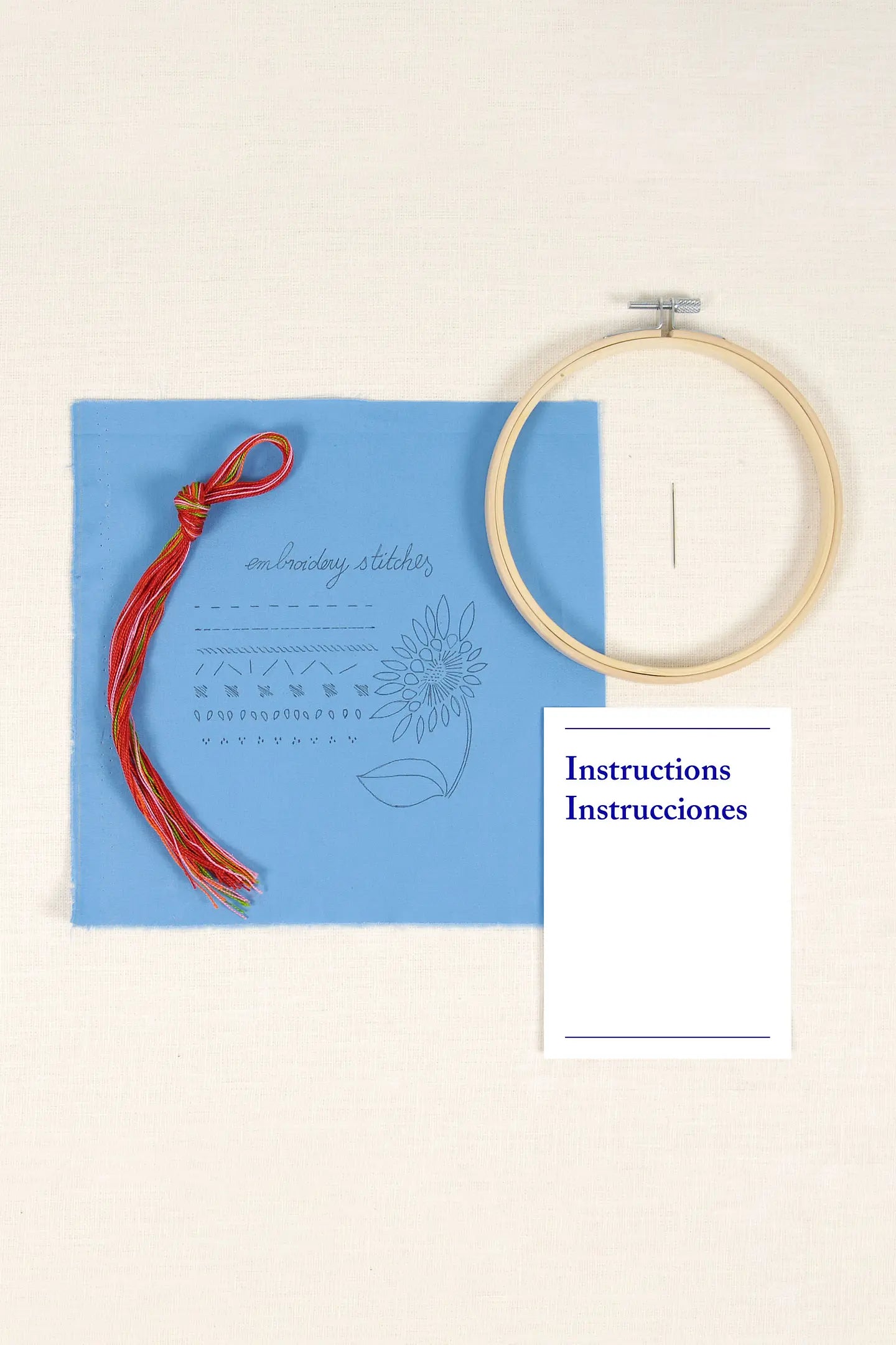 Contenido del kit de iniciación al bordado DMC con tela impresa azul, hilos, aguja, bastidor e instrucciones