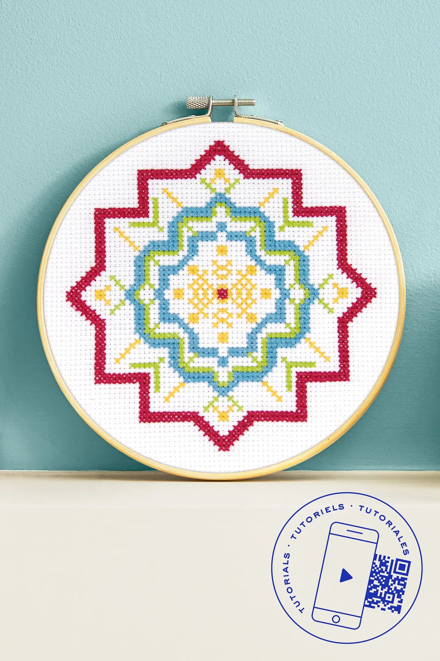 Kit de iniciación al punto de cruz DMC con diseño geométrico en rojo, azul, verde y amarillo en bastidor de madera