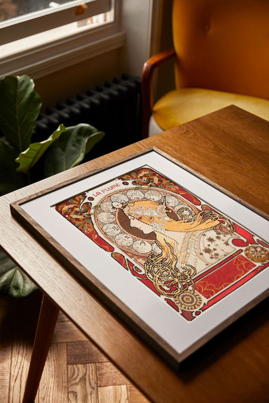 Kit punto de cruz DMC Zodiaco inspirado en Alphonse Mucha con diseño Art Nouveau sobre tela Aida blanca y detalles ornamentales.