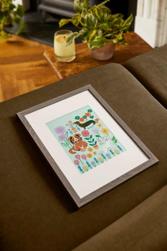 Kit de punto de cruz DMC “Perros en el Jardín” de Marie-Dominique Procureur con perros entre flores veraniegas bordado en tela Aida 14 ct.