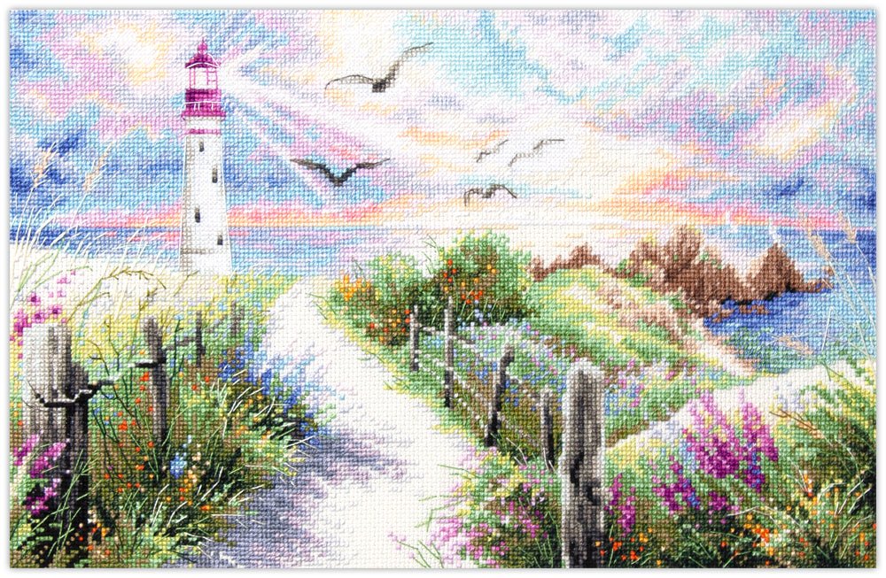 Kit de punto de cruz Magic Needle The Light of Home con diseño de faro costero al atardecer, sendero de flores silvestres y mar para bordado y decoración.