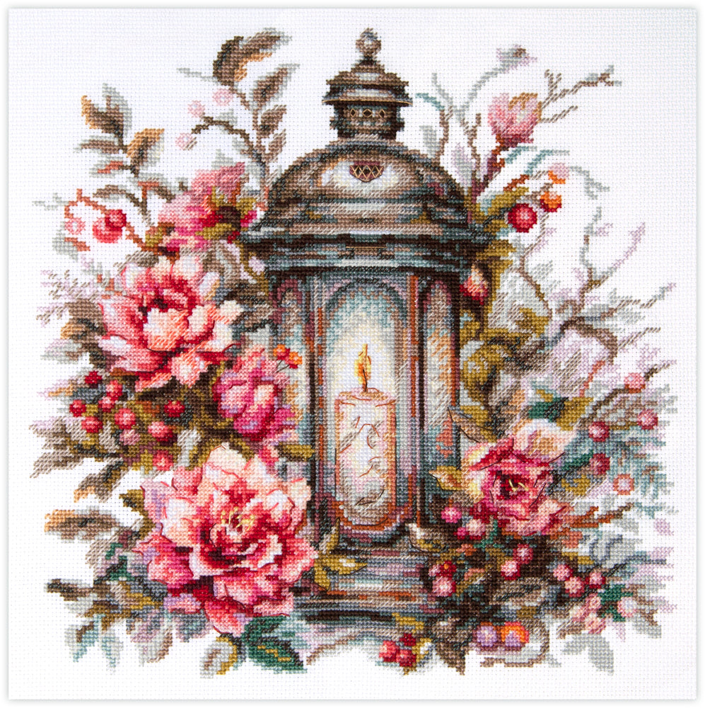 Kit de punto de cruz Lantern in Bloom con linterna iluminada rodeada de flores en diseño elegante y detallado.