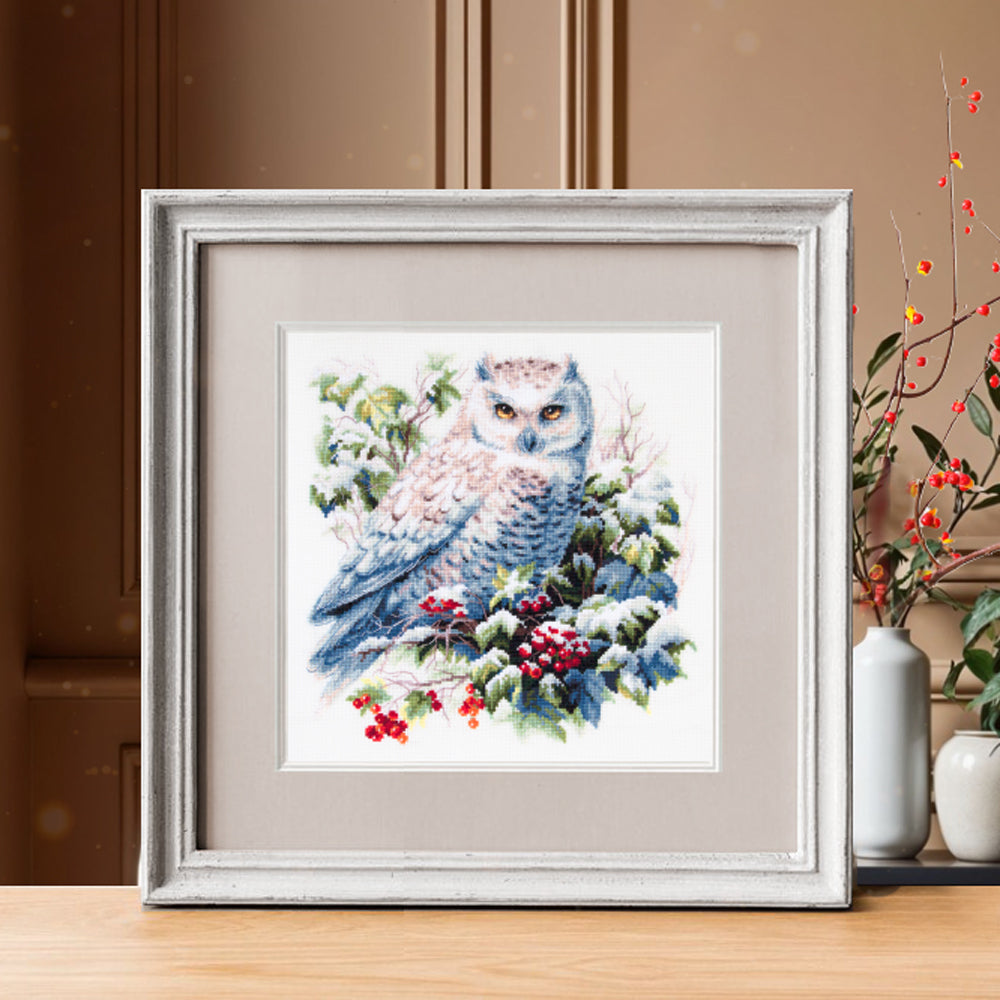 Kit de punto de cruz Magic Needle “Búho Nevado” 26×26 cm en Aida 16 ct Zweigart, 37 colores Gamma; diseño de búho blanco entre hojas y bayas cubiertas de nieve.