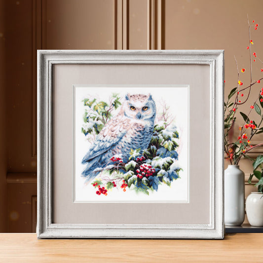 Kit de punto de cruz Magic Needle “Búho Nevado” 26×26 cm en Aida 16 ct Zweigart, 37 colores Gamma; diseño de búho blanco entre hojas y bayas cubiertas de nieve.