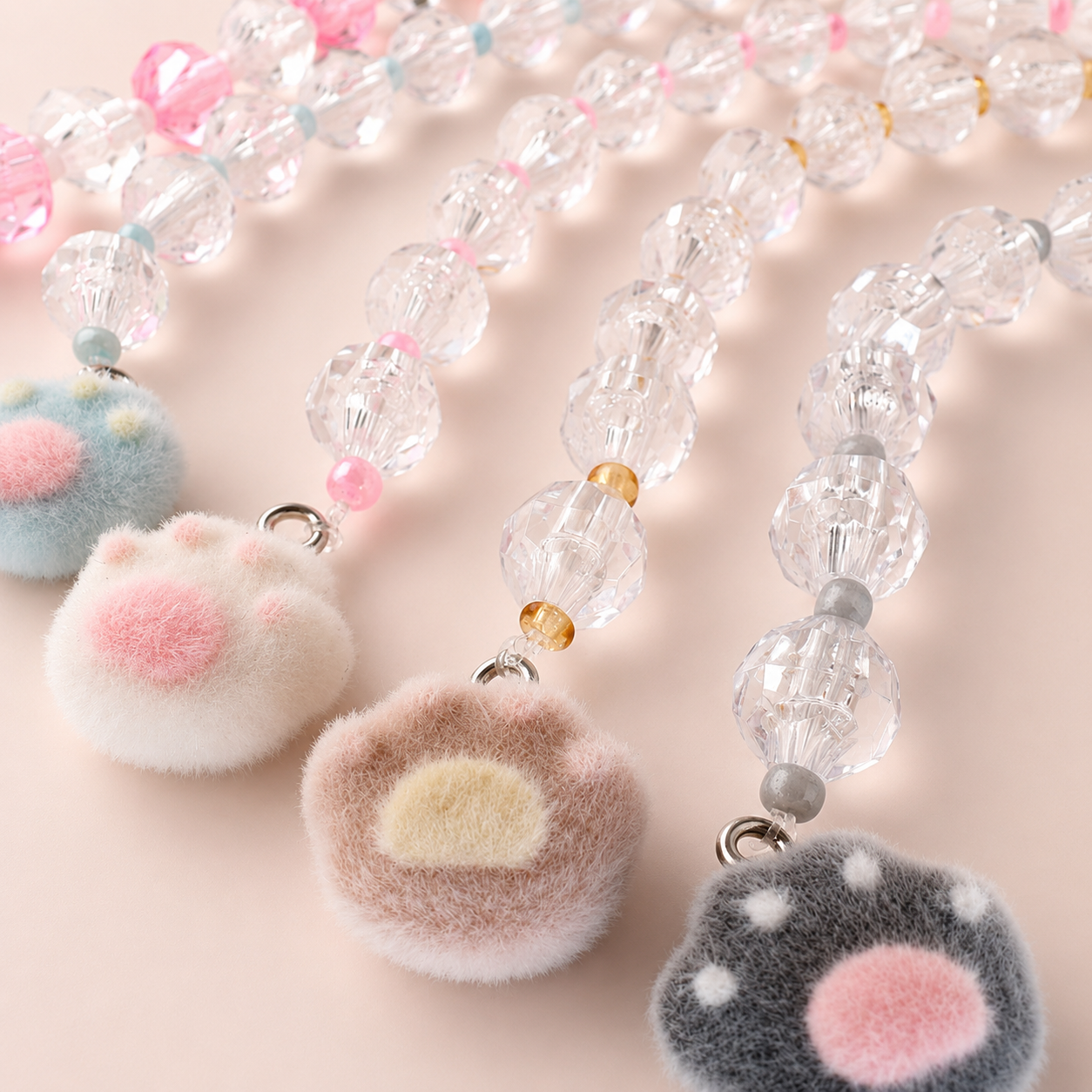 Composición de buscatijeras con charms de huella de gato, cierre metálico y abalorios transparentes para costura y punto de cruz.

